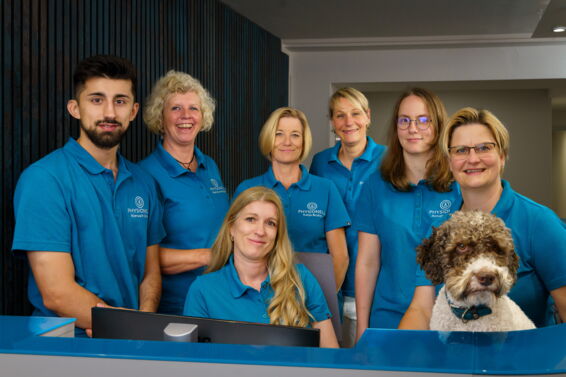 Das Praxis Team steht draußen hintereinander gereiht vor dem Praxisschild.